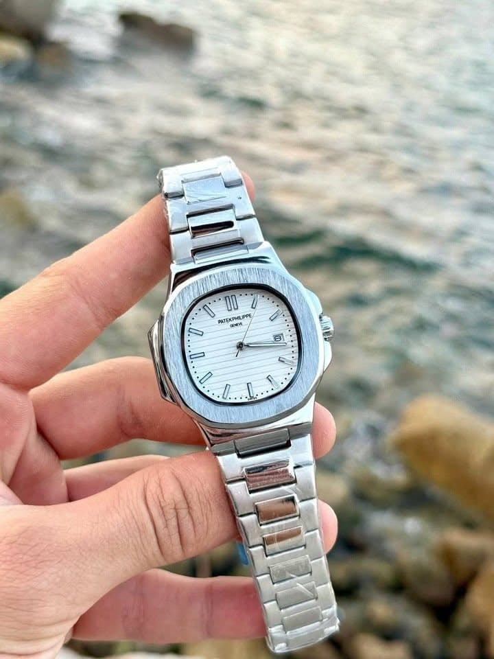 White dial metal watch held by the water