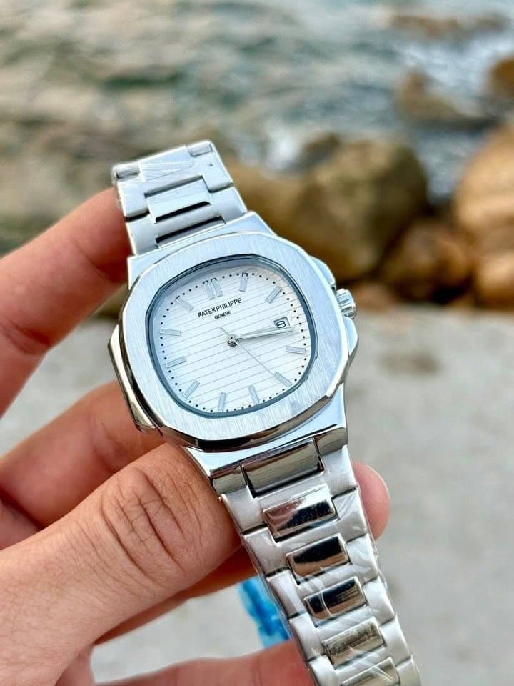 White dial metal watch angled in hand